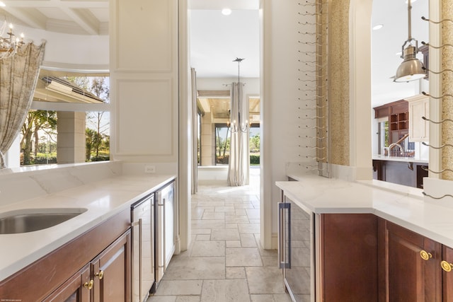 bar with light stone counters, coffered ceiling, beverage cooler, beamed ceiling, and hanging light fixtures