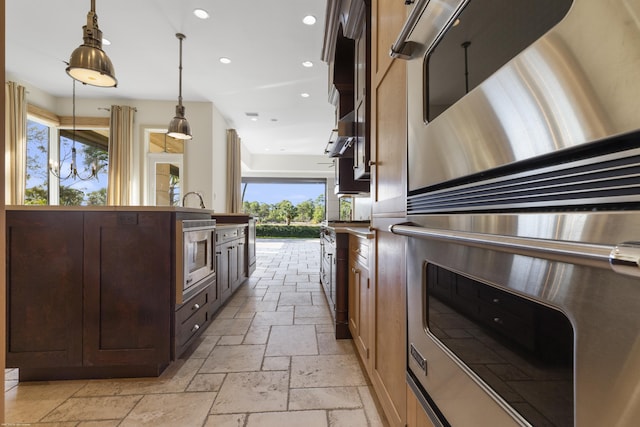 kitchen with double oven, built in microwave, dark brown cabinets, and pendant lighting