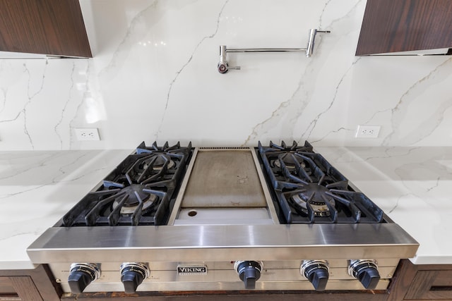 interior details featuring backsplash, light stone countertops, and range