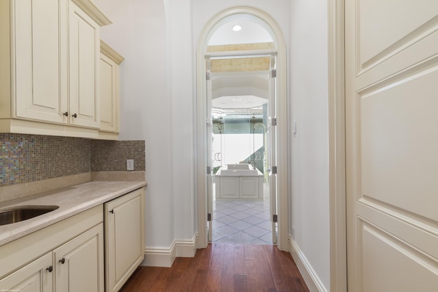 interior space with decorative backsplash, dark wood-type flooring, and cream cabinets