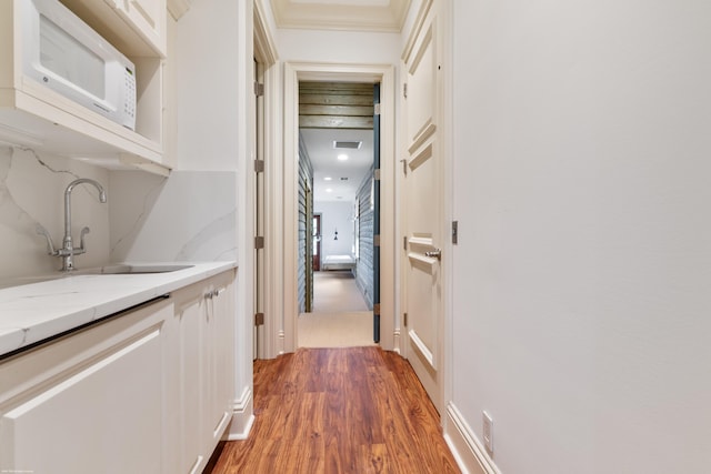 hall featuring crown molding, hardwood / wood-style floors, and sink