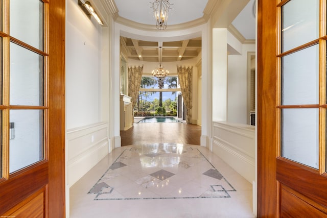 corridor featuring beam ceiling, a chandelier, coffered ceiling, and ornamental molding