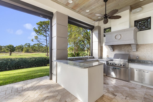 view of patio with an outdoor kitchen, ceiling fan, a wet bar, and a grill