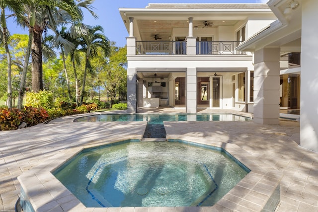 back of house with ceiling fan, a patio area, a balcony, and a swimming pool with hot tub