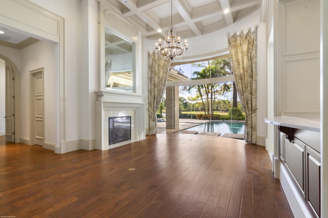 unfurnished living room featuring beam ceiling, a towering ceiling, dark hardwood / wood-style flooring, and coffered ceiling