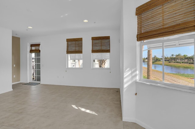 spare room with a water view and light tile patterned floors