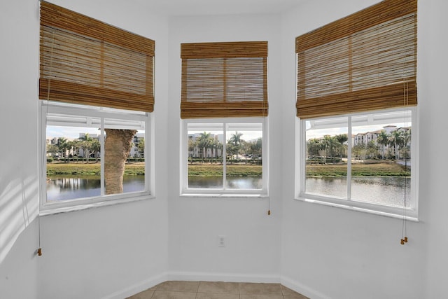 empty room with a water view and light tile patterned floors