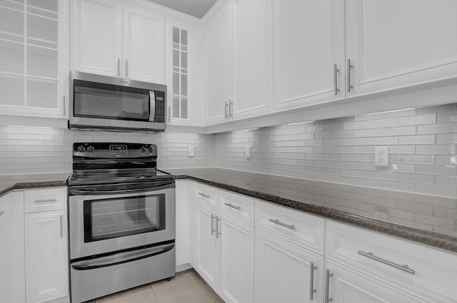 kitchen with white cabinets, dark stone countertops, light tile patterned floors, and appliances with stainless steel finishes