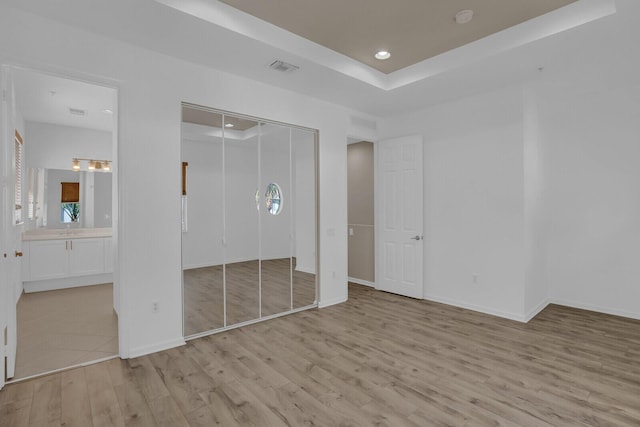 unfurnished bedroom with ensuite bath and light hardwood / wood-style flooring