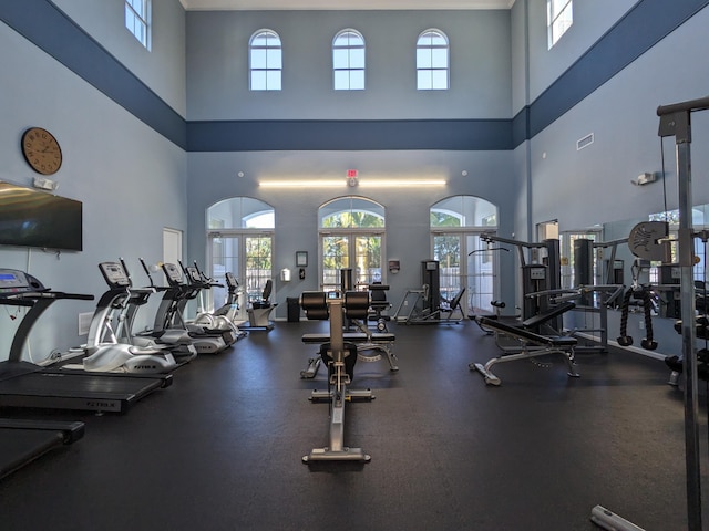 gym with a high ceiling and french doors