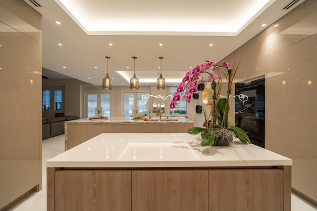 kitchen with light stone countertops, french doors, sink, hanging light fixtures, and a large island