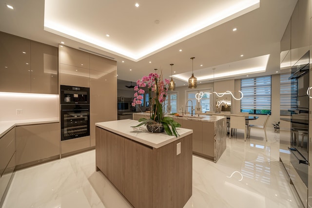 kitchen featuring a raised ceiling, a large island, beverage cooler, and decorative light fixtures