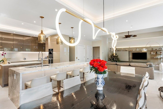 tiled dining area featuring a raised ceiling and sink