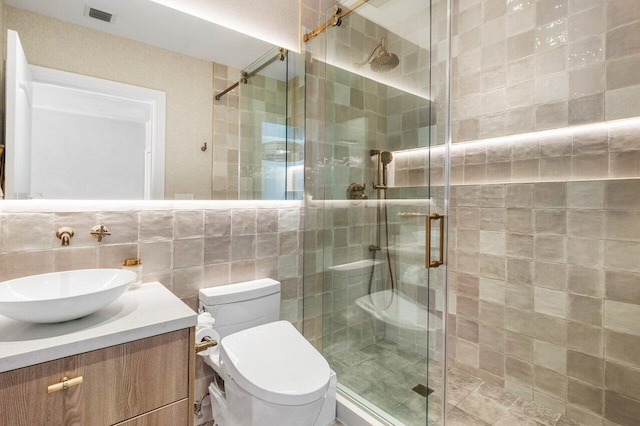 bathroom with tasteful backsplash, vanity, tile walls, toilet, and a shower with shower door