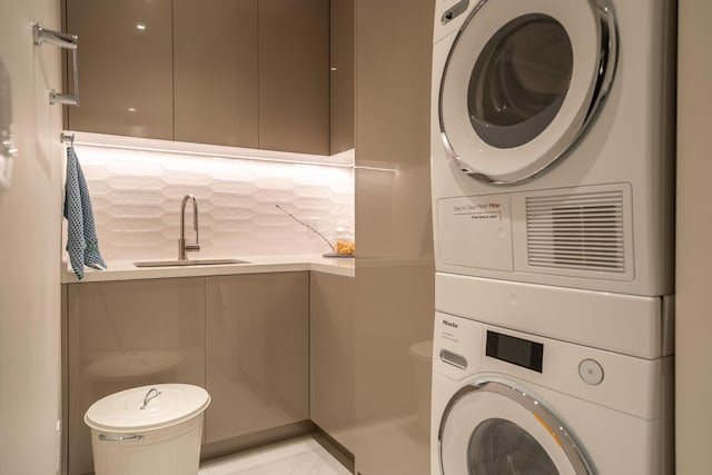 laundry area with stacked washer / drying machine and sink