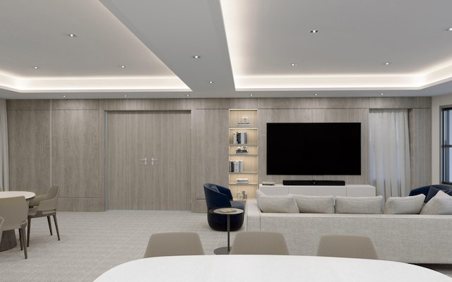 living room featuring a tray ceiling, wood walls, and light colored carpet