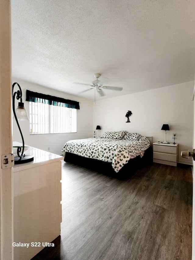 bedroom with a textured ceiling, ceiling fan, and dark wood-type flooring