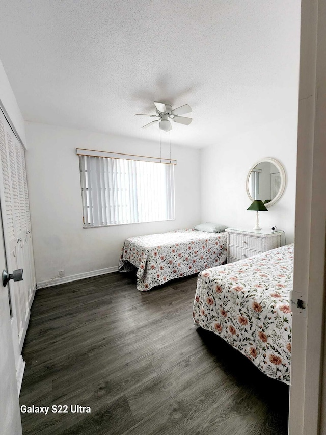 bedroom with a textured ceiling, ceiling fan, dark wood-type flooring, and a closet