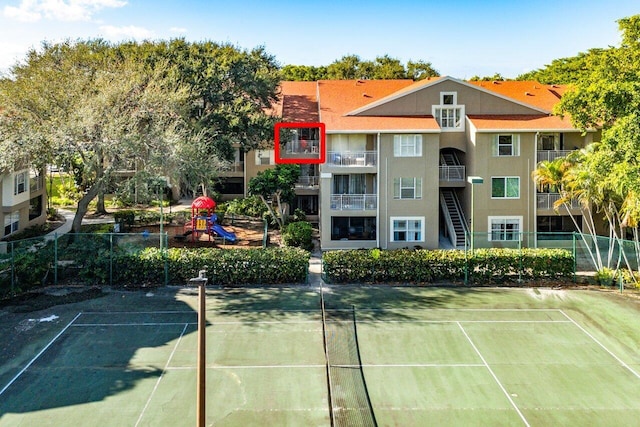 view of tennis court featuring a playground