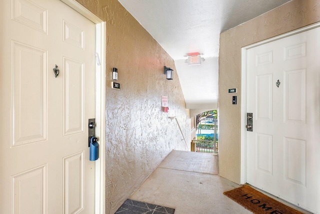 carpeted foyer entrance featuring a textured ceiling