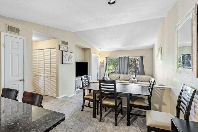 carpeted dining area with lofted ceiling