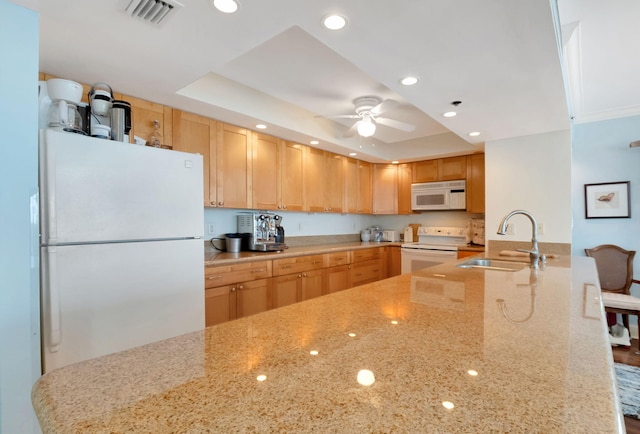 kitchen with light brown cabinets, white appliances, a raised ceiling, and sink