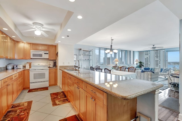 kitchen with sink, kitchen peninsula, pendant lighting, white appliances, and a kitchen bar