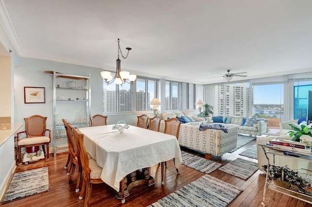 dining room featuring ceiling fan with notable chandelier, wood-type flooring, ornamental molding, and a wealth of natural light