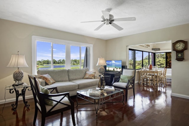 living room featuring a textured ceiling, ceiling fan, a healthy amount of sunlight, and dark hardwood / wood-style floors