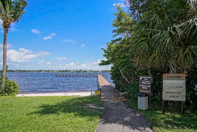 view of dock featuring a beach view and a water view