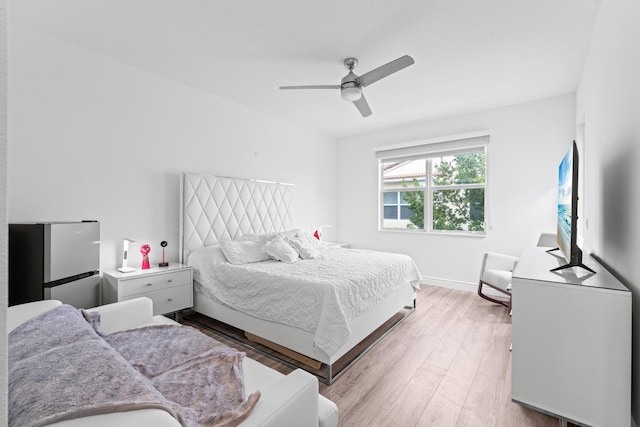 bedroom featuring light hardwood / wood-style flooring, ceiling fan, and stainless steel refrigerator