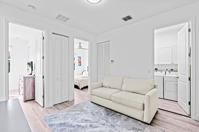 living room featuring washer and clothes dryer, ceiling fan, and light hardwood / wood-style floors