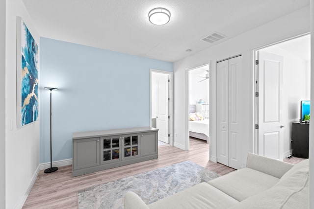 living room with a textured ceiling, light wood-type flooring, and ceiling fan