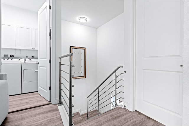 laundry room with cabinets, light wood-type flooring, and washing machine and clothes dryer