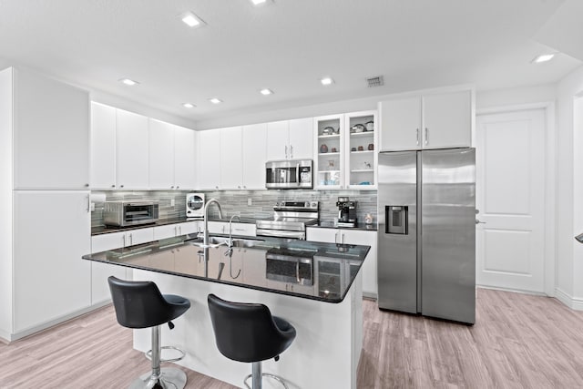 kitchen featuring appliances with stainless steel finishes, sink, light hardwood / wood-style flooring, white cabinetry, and an island with sink