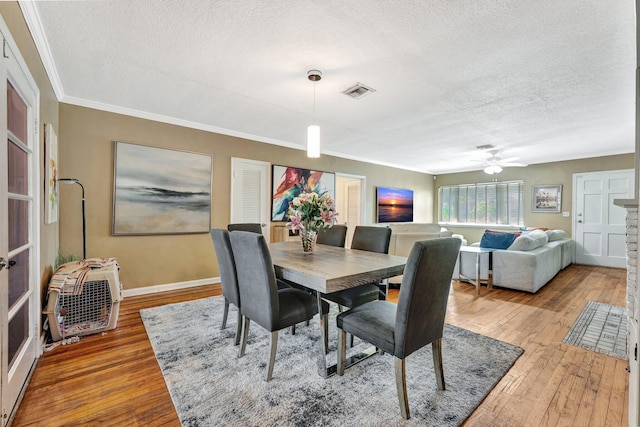 dining room featuring a textured ceiling, hardwood / wood-style flooring, ceiling fan, and crown molding