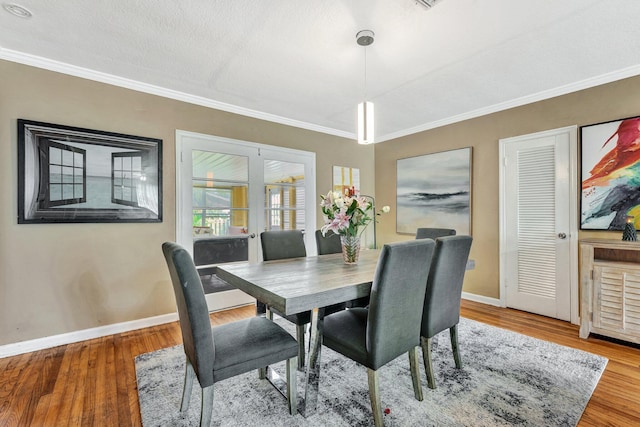 dining room featuring hardwood / wood-style flooring, crown molding, and a textured ceiling