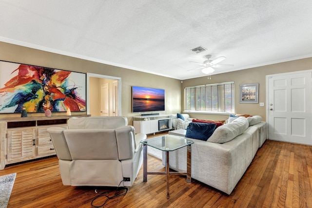 living room featuring ceiling fan, wood-type flooring, and a textured ceiling