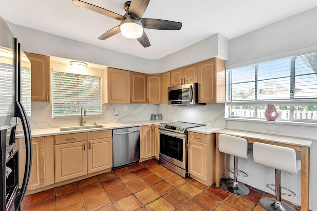 kitchen featuring light brown cabinets, sink, ceiling fan, tasteful backsplash, and stainless steel appliances