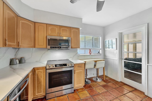 kitchen featuring decorative backsplash, light brown cabinetry, ceiling fan, and appliances with stainless steel finishes