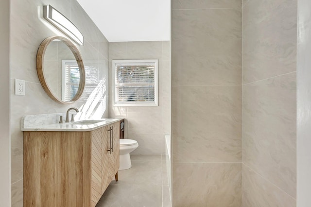 bathroom with tile patterned floors, vanity, toilet, and tile walls