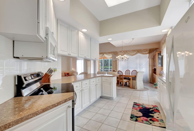 kitchen featuring kitchen peninsula, white appliances, pendant lighting, white cabinets, and light tile patterned flooring