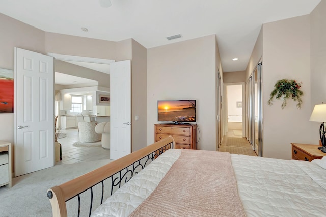 bedroom featuring ensuite bathroom and light colored carpet