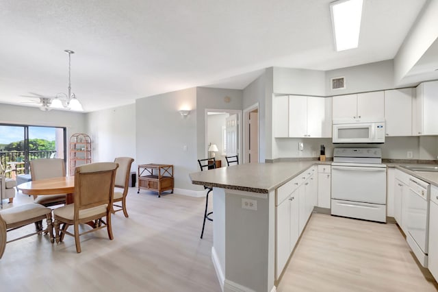 kitchen featuring white appliances, an inviting chandelier, white cabinets, light wood-type flooring, and kitchen peninsula