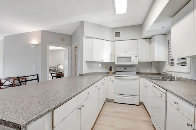 kitchen featuring white appliances, sink, white cabinetry, light hardwood / wood-style floors, and kitchen peninsula