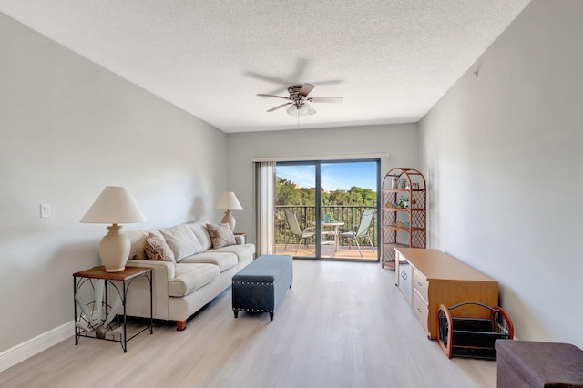 living room featuring ceiling fan, light hardwood / wood-style floors, and a textured ceiling