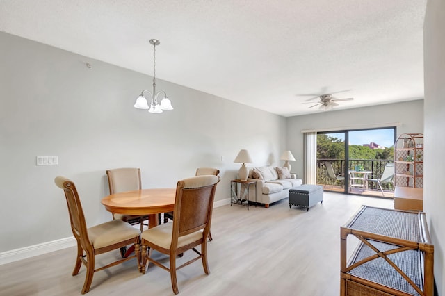 dining space with ceiling fan with notable chandelier and light hardwood / wood-style flooring