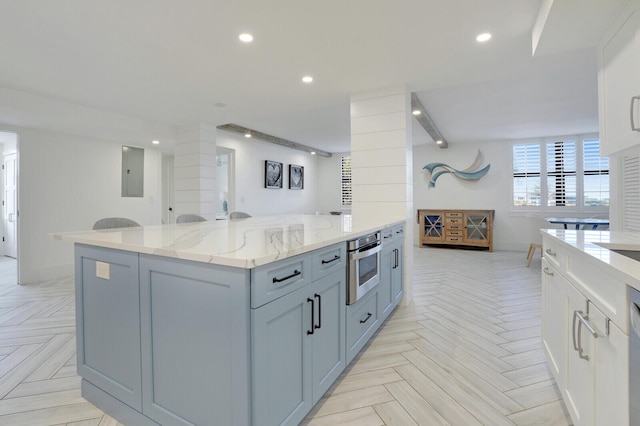 kitchen featuring light stone counters, a center island, stainless steel oven, and light parquet floors