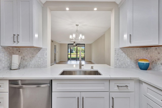 kitchen with dishwasher, an inviting chandelier, white cabinets, sink, and light stone counters