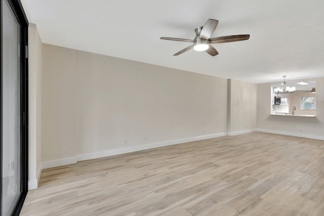 spare room featuring ceiling fan with notable chandelier, light hardwood / wood-style floors, and sink